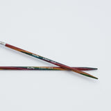 KnitPro Symfonie 2 fixed circular knitting needles with swivel cable, 40 cm - Two wooden knitting needles with a multicolor rainbow finish and silver metal tips, crossed on a plain white background. The needles have white printed text reading 'Kraft-Pa 3.